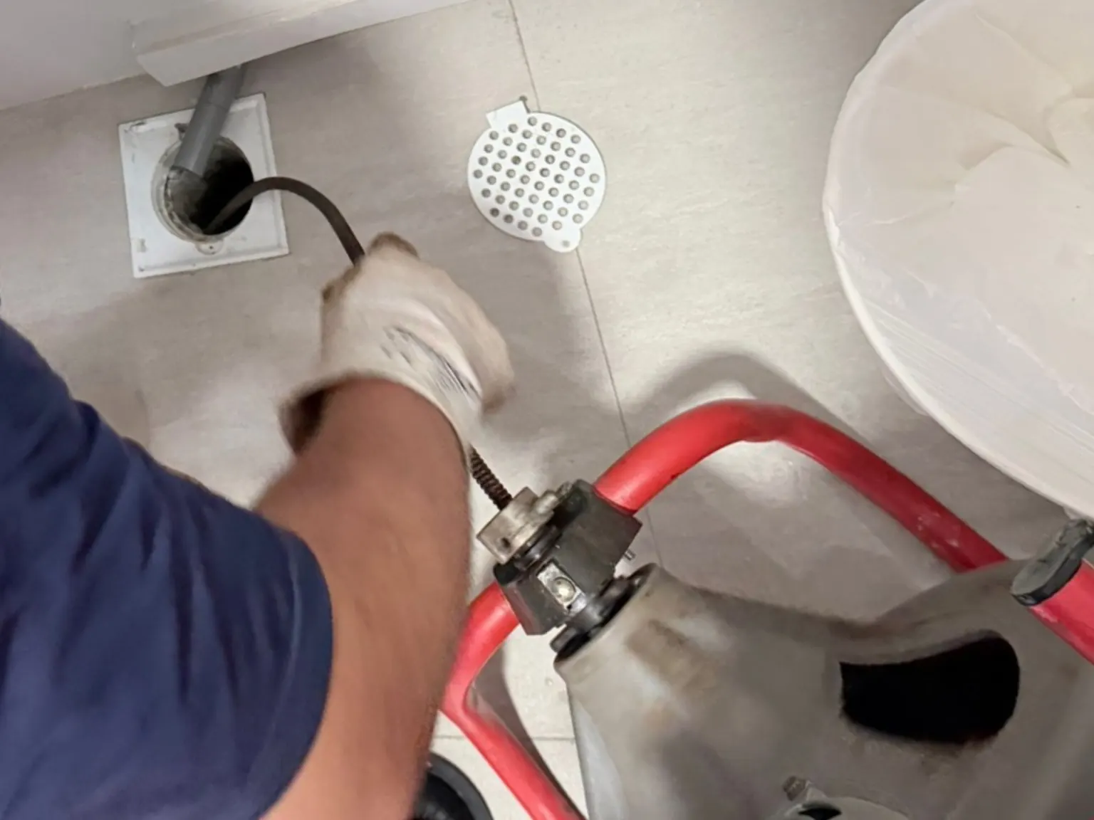 Toilet floor trap choke clearing using drain clearing equipment